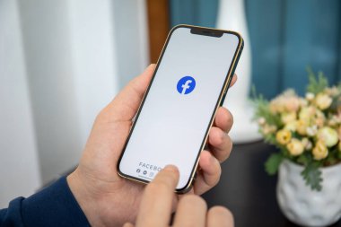 Alanya, Türkiye - 8 Ocak 2020: İnsan eli iPhone 12 Pro Max Gold ve sosyal ağ hizmetleri kuryesi Facebook ekranda