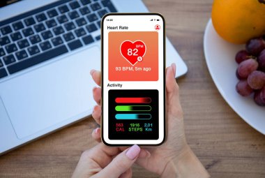 Kadın elleri uygulama kalbi ve faaliyeti olan telefonu ofisteki masanın üzerinde tutuyor.