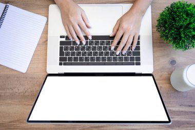 Dizüstü bilgisayar klavyesinde kadın elleri ve ofiste yalnız ekran. 