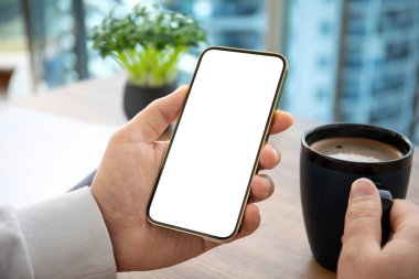 Ofisteki ahşap masadaki izole ekranlı altın telefonu tutan erkek el. 