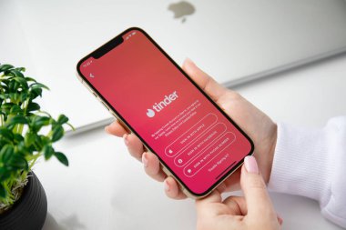 Alanya, Türkiye - 4 Aralık 2020: Kadın eli iPhone 12 Pro Max Gold ile çevrimiçi İnternet ağı Tinder ekranında.