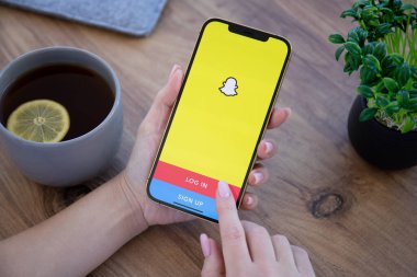 Alanya, Türkiye - 6 Aralık 2020: Kadın eli iPhone 12 Pro Max Gold ve sosyal ağ servisi Snapchat ekranda. iPhone Apple tarafından oluşturuldu ve geliştirildi..