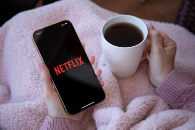 Alanya, Türkiye - 16 Aralık 2020: iPhone 12 Pro Max Gold 'u çok uluslu eğlence şirketi Netflix ile elinde tutan kadın ekranda yayın yapan medya ve video sunuyor.