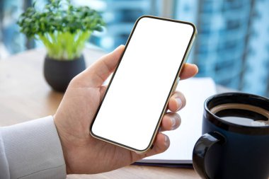 Ofisteki masanın arka planında izole ekranı olan altın telefonu tutan erkek eller. 