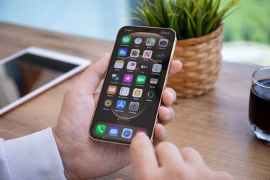 Alanya, Türkiye - 7 Nisan 2021: İnsan eli iPhone 12 Pro Max Gold ile ana ekran IOS 14 ekranında.