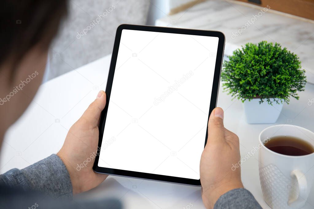 male hands hold computer tablet upright with isolated screen over table in office 