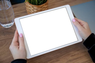 Ofisteki ahşap masada beyaz bilgisayar tableti tutan erkek elleri. 