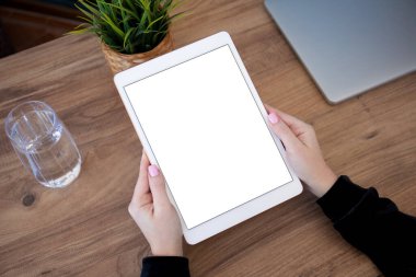 Ofisteki ahşap masada beyaz bilgisayar tableti tutan erkek elleri. 