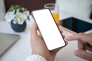 Ofisteki masadaki tek ekran ekranlı telefonu tutan erkek eller. 