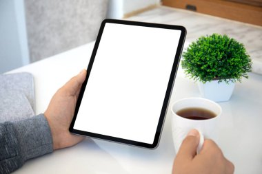 Erkek eller bilgisayarın tabletini ayakta tutarken masadaki izole ekranla birlikte. 