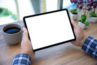 Kafe 'deki masasının üzerinde izole ekranlı bilgisayar tableti tutan erkek elleri 