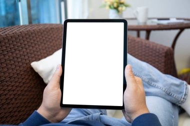 Erkek eller, odanın arka planında izole ekran olan bilgisayar tabletini tutuyor. 