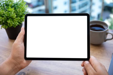 Ofisteki masadaki izole ekranlı bilgisayar tabletini tutan erkek elleri
