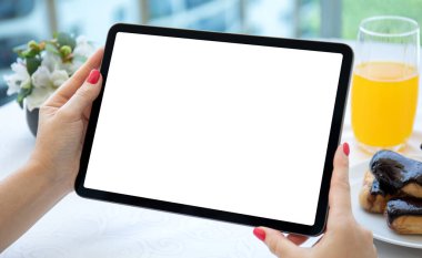 Kadın elleri kafeteryadaki masanın üzerinde izole ekran tableti tutuyor. 