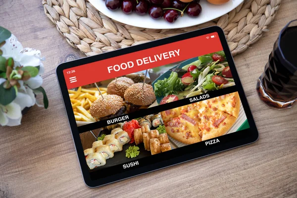 computer tablet with app food delivery on screen over table in cafe