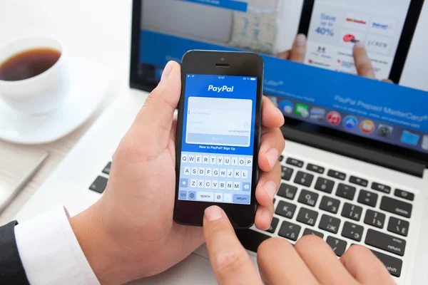 Empresario sosteniendo iPhone con aplicación PayPal en la pantalla en una ba — Foto de Stock