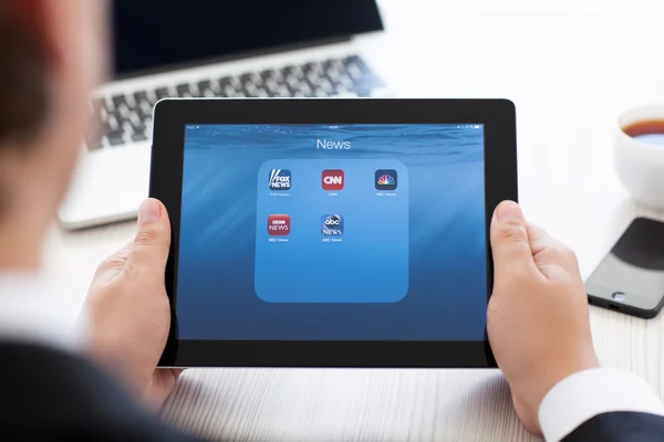 Businessman holding iPad with news app on the screen — Stock Photo, Image