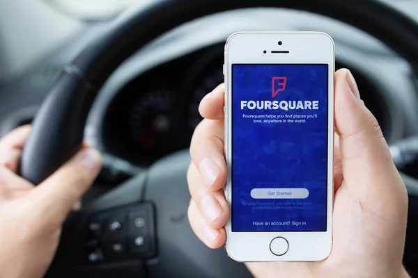 IPhone 5S app Foursquare in hands of the driver car — Stock Photo, Image