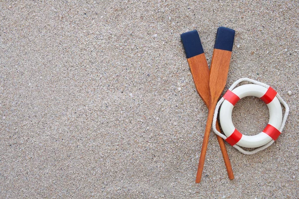 Paletas y boya salvavidas tumbadas sobre una arena — Foto de Stock