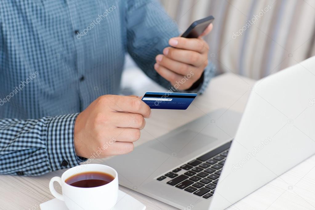 man makes the payment by credit card on the laptop 