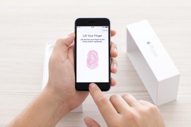 Alushta - 23 Ekim 2014: Adam masadaki iPhone 6 Space Gray 'deki parmak izi sensör dokunmatik kimliğini tarıyor. Dokunmatik Kimlik Apple şirketi tarafından oluşturuldu ve geliştirildi.