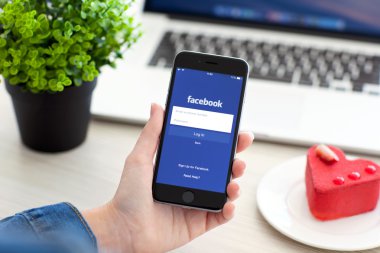 Alushta - 28 Ekim 2014: Ekranda sosyal ağ hizmetleri Facebook 'u olan iPhone 6 Space Gray' i tutan kadın. iPhone 6 Apple Inc. tarafından oluşturuldu ve geliştirildi.