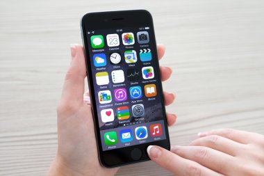 Alushta - 23 Ekim 2014: Masanın üzerinde elinde yeni bir iPhone 6 Space Gray tutan kadın. iPhone 6 Apple Inc. tarafından oluşturuldu ve geliştirildi.