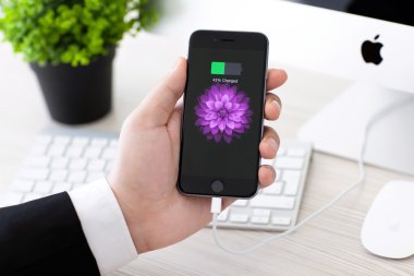 Alushta - 2 Kasım 2014: Ekranda pil simgesi olan iPhone 6 Space Gray 'i tutan adam. iPhone 6 Apple Inc. tarafından oluşturuldu ve geliştirildi.