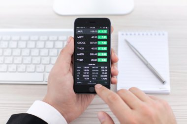 Alushta - 3 Kasım 2014: Ekranda Apple Stocks uygulaması olan bir iPhone 6 Space Gray tutan bir iş adamı. iPhone 6 Apple Inc. tarafından oluşturuldu ve geliştirildi.