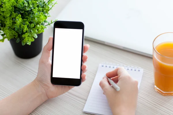 Donne mano tenendo il telefono e scrivendo in un taccuino — Foto Stock