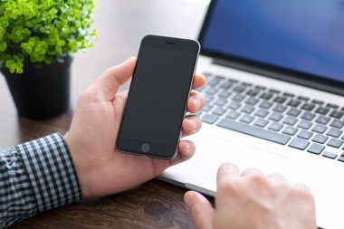 Alushta - 20 Kasım 2014: Man switch on the new iPhone 6 Space Gray holding it over the table. iPhone 6 Apple Inc. tarafından oluşturuldu ve geliştirildi.