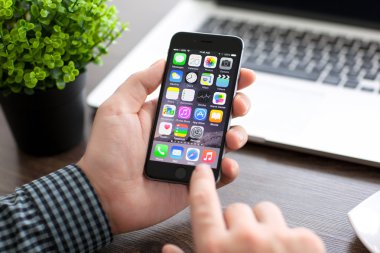 Alushta - 20 Kasım 2014: Elinde yeni telefon tutan adam Macbook ile masanın üzerinde Uzay Gri 6 'yı tutuyor. iPhone 6 Apple Inc. tarafından oluşturuldu ve geliştirildi