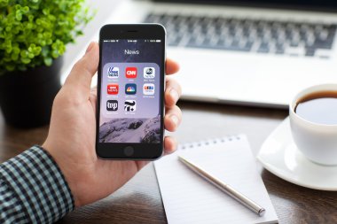 Alushta - 20 Kasım 2014: Ekranda popüler haber uygulamalarının yer aldığı iPhone 6 Space Gray 'i elinde tutan iş adamı. iPhone 6 Apple Inc. tarafından oluşturuldu ve geliştirildi.