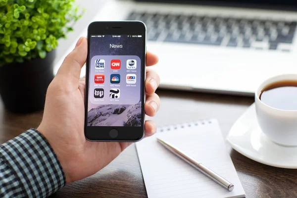 Alushta 2014年11月20日 商人手持Iphone Space Gray 屏幕上有流行的新闻应用程序 Iphone 6是由Apple Inc创建和开发的 — 图库照片