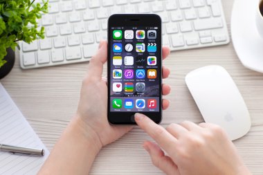 Alushta - 25 Ekim 2014: iMac 'le masanın üzerinde elinde yeni bir iPhone 6 Space Gray tutan kadın. iPhone 6 Apple Inc. tarafından oluşturuldu ve geliştirildi