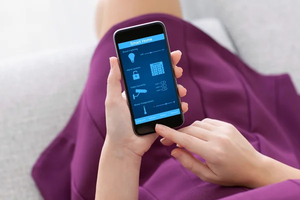 Mädchen hält Handy mit Programm Smart Home auf dem Bildschirm — Stockfoto
