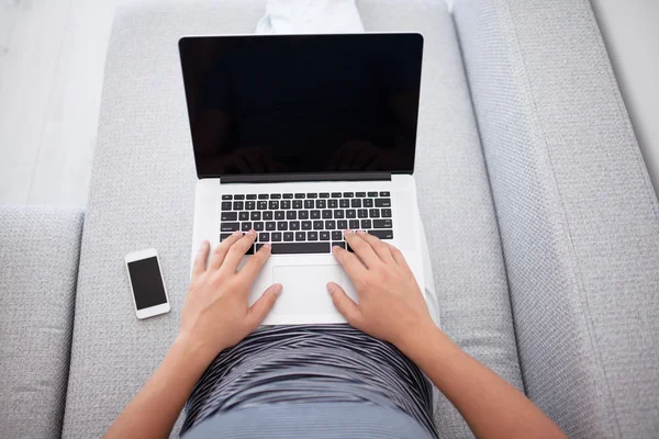 Человек лежит с телефоном и печатает на ноутбуке — стоковое фото