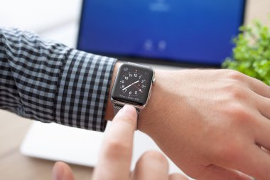 Alushta - 11 Ağustos 2015: Masasında Apple Watch ve Macbook olan adam eli. Apple Watch Apple tarafından yaratıldı ve geliştirildi..