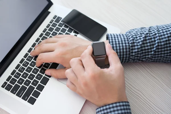 Мужские руки с часами и телефон с ноутбуком — стоковое фото