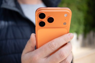 Alanya, Türkiye - 24 Ocak 2026: Telefon Apple iPhone 17 Pro Maksimum Kozmik Portakal, arka taraf, açık havada erkeklerin elinde tutun