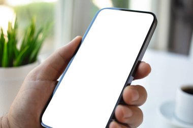 Kafe ofisinde kahve fincanı ve masasının üzerinde izole bir ekranı olan erkek el ele tutuşan telefon.