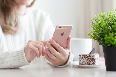 Alushta - 25 Ekim 2015: Kafede iPhone 6 S Rose Gold 'u elinde tutan kadın. iPhone 6S Apple tarafından oluşturuldu ve geliştirildi..