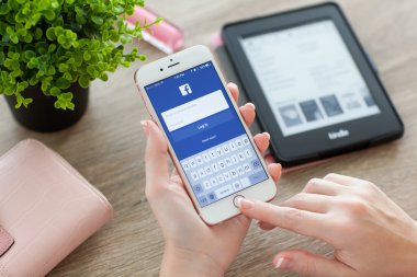 İPhone 6s tutan kadın Facebook üstünde perde ile Rose Altın