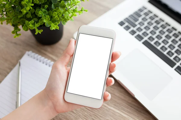 Mano femminile in possesso di un telefono cellulare con schermo isolato e laptop — Foto Stock