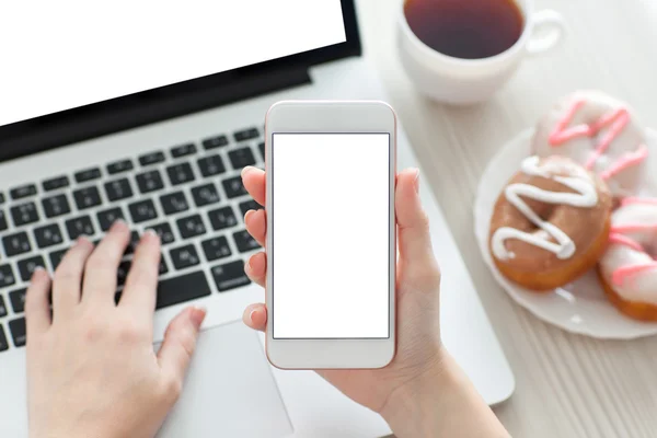 Vrouwelijke hand met een telefoon met geïsoleerde scherm en laptop — Stockfoto