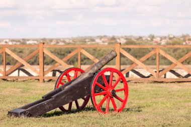 Kırmızı tekerlekleri olan bir arabada antika bir top.