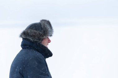 Kar yağışı altında uçuş ceketli bir adam.