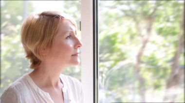 Pencerede çay içen bir kadın zevkle gözlerini kapatıyor.