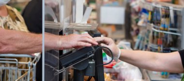 Bir adam alışverişini süpermarkette kartla öder.