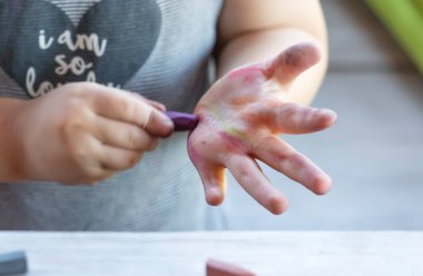 Bebek eline mum boya kalemi çiziyor.